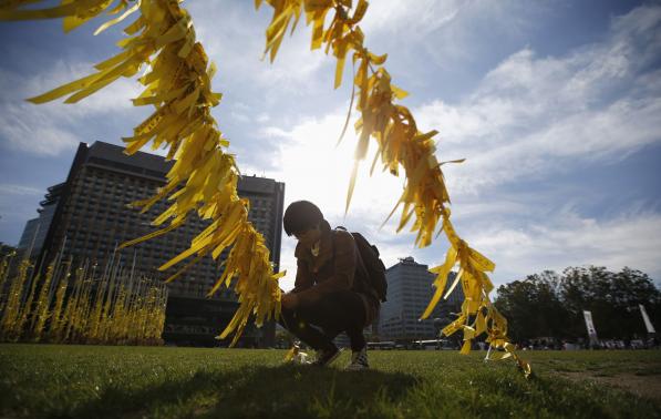 A man ties a yellow ribbon dedicated to victims onboard the sunken ferry Sewol, on a cable at Seoul City Hall Plaza, in Seoul